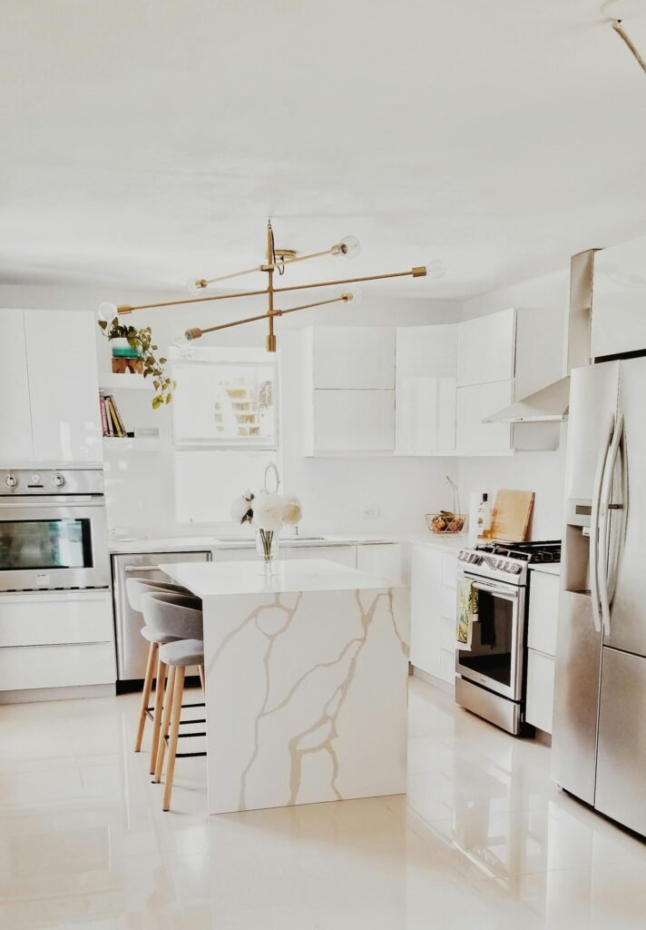 A bright, modern kitchen featuring white cabinetry, stainless steel appliances, and minimalist decor.